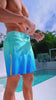 Man in faded ocean swim trunks near a pool.