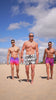 Group of men wearing swim trunks walking on a sandy beach