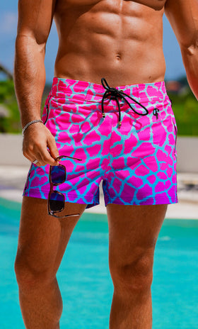 Person wearing pink and blue patterned swim shorts by a pool.