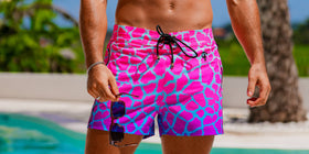 Person wearing pink and blue patterned swim shorts by a poolside.