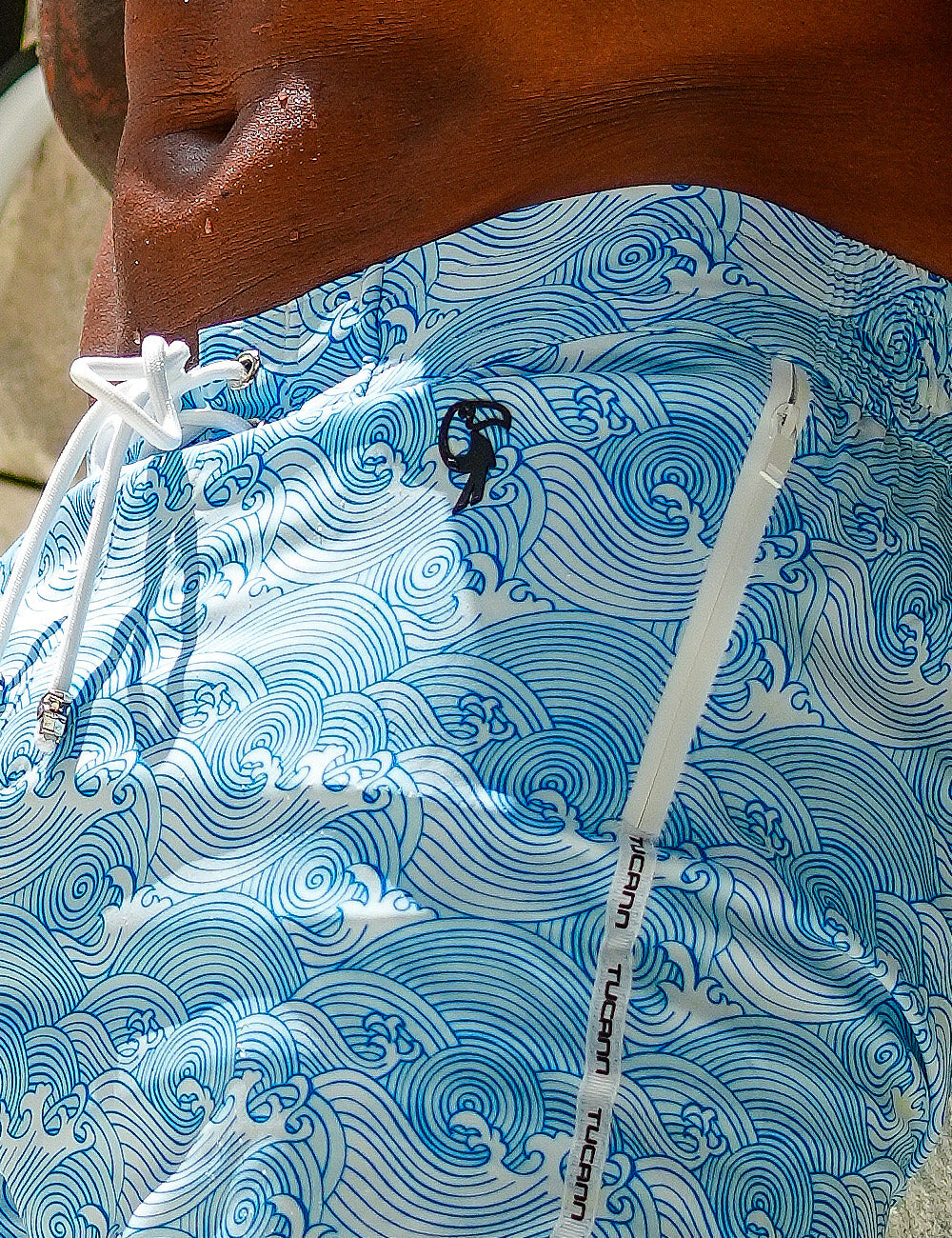 Close-up of light blue swim trunks with a swirling wave pattern.
